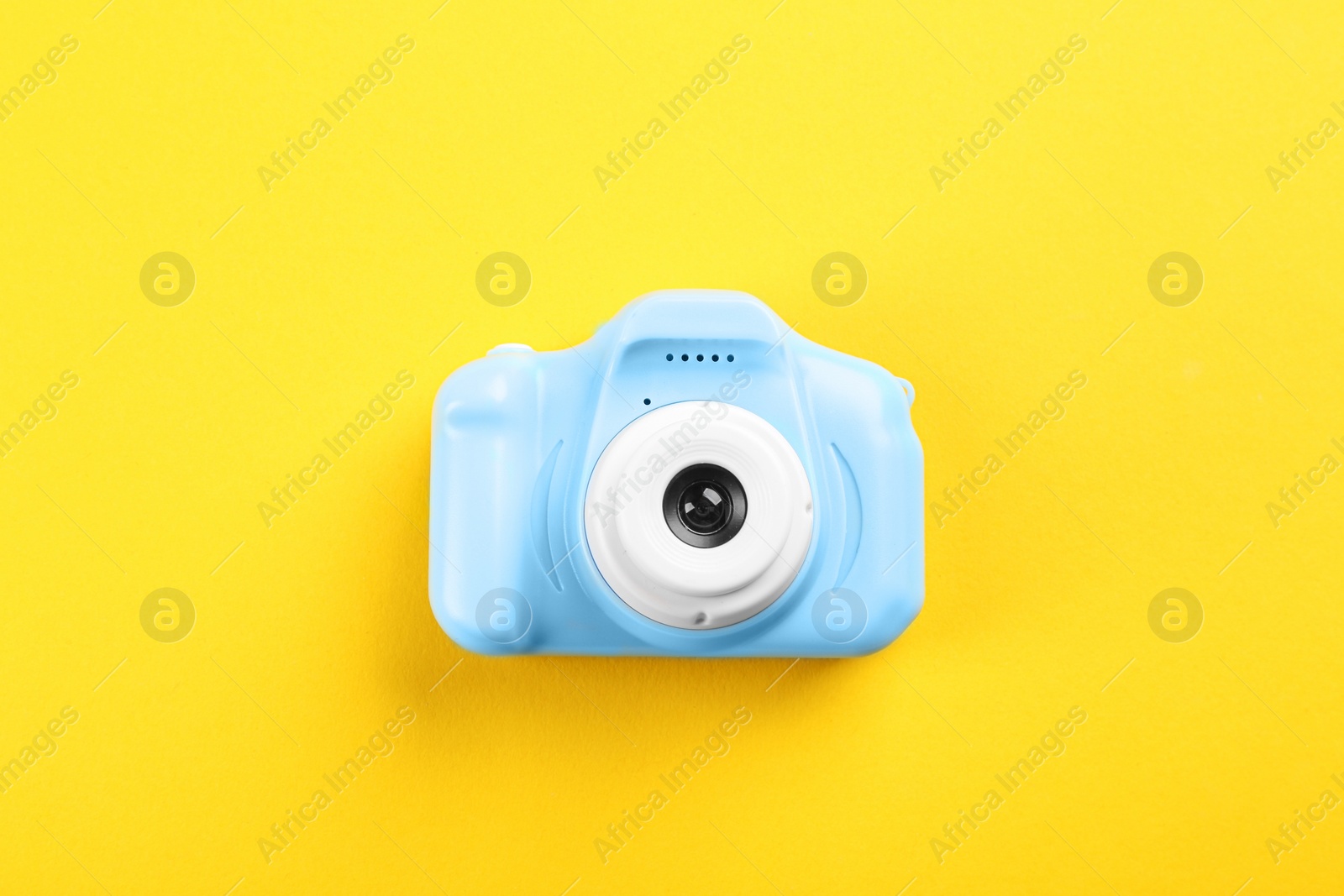 Photo of Light blue toy camera on yellow background, top view