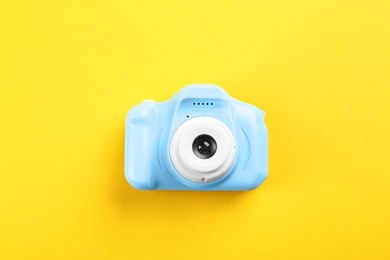 Light blue toy camera on yellow background, top view