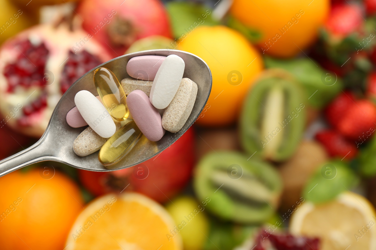 Photo of Different vitamin pills in spoon over fresh fruits, top view. Space for text