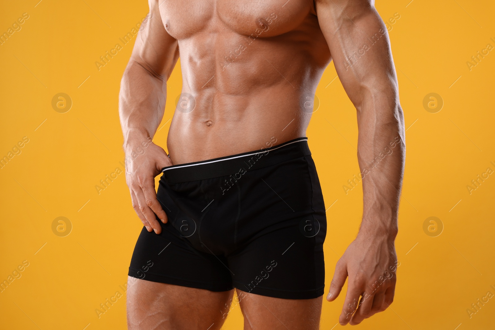 Photo of Young man is stylish black underwear on orange background, closeup