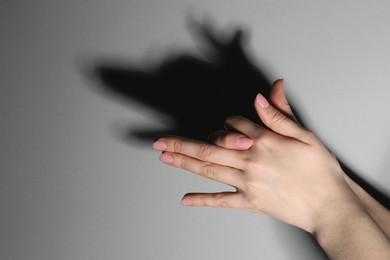 Shadow puppet. Woman making hand gesture like dog on grey background, closeup