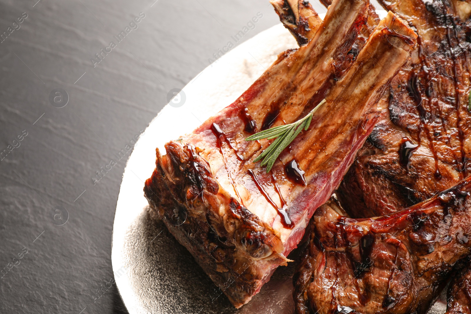 Photo of Delicious grilled ribs with rosemary on table, closeup