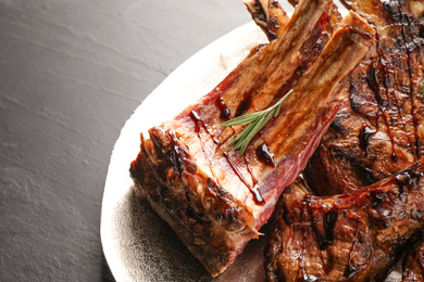 Delicious grilled ribs with rosemary on table, closeup