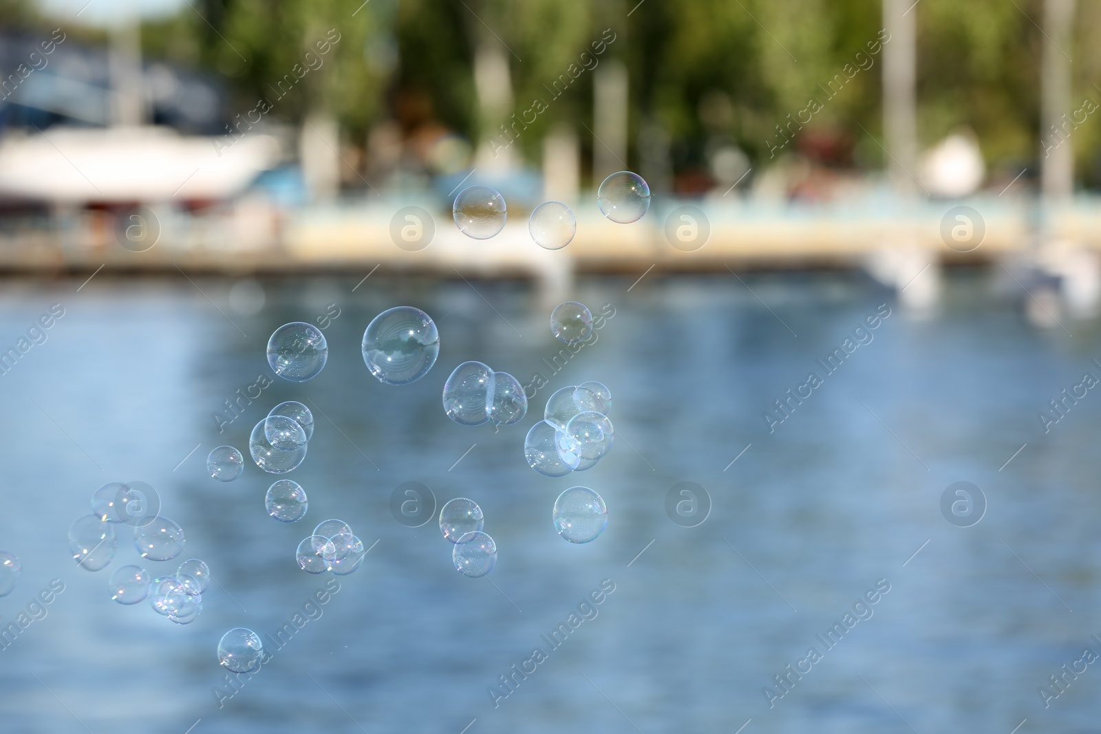 Photo of Beautiful translucent soap bubbles outdoors on sunny day. Space for text