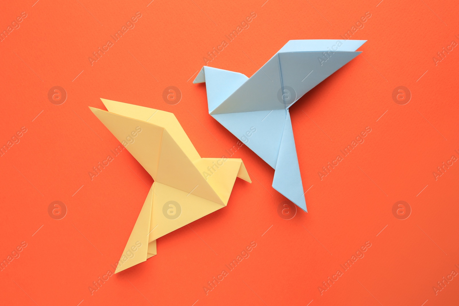 Photo of Beautiful colorful origami birds on orange background, flat lay