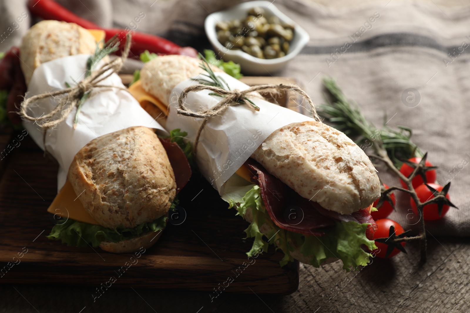 Photo of Delicious sandwiches with bresaola, cheese and lettuce on wooden table, closeup