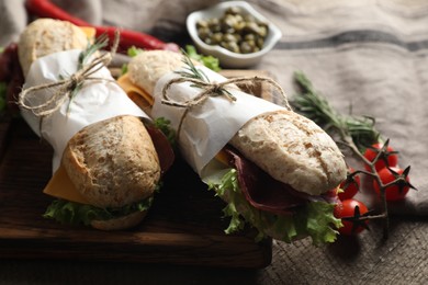Photo of Delicious sandwiches with bresaola, cheese and lettuce on wooden table, closeup