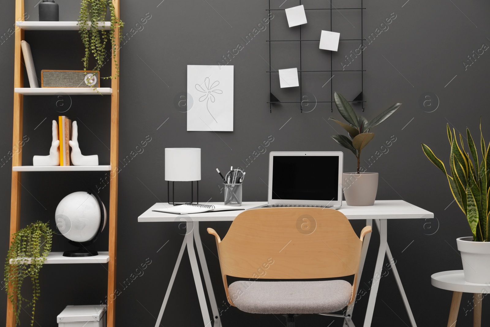 Photo of Cozy workplace with modern laptop on desk and comfortable chair at home