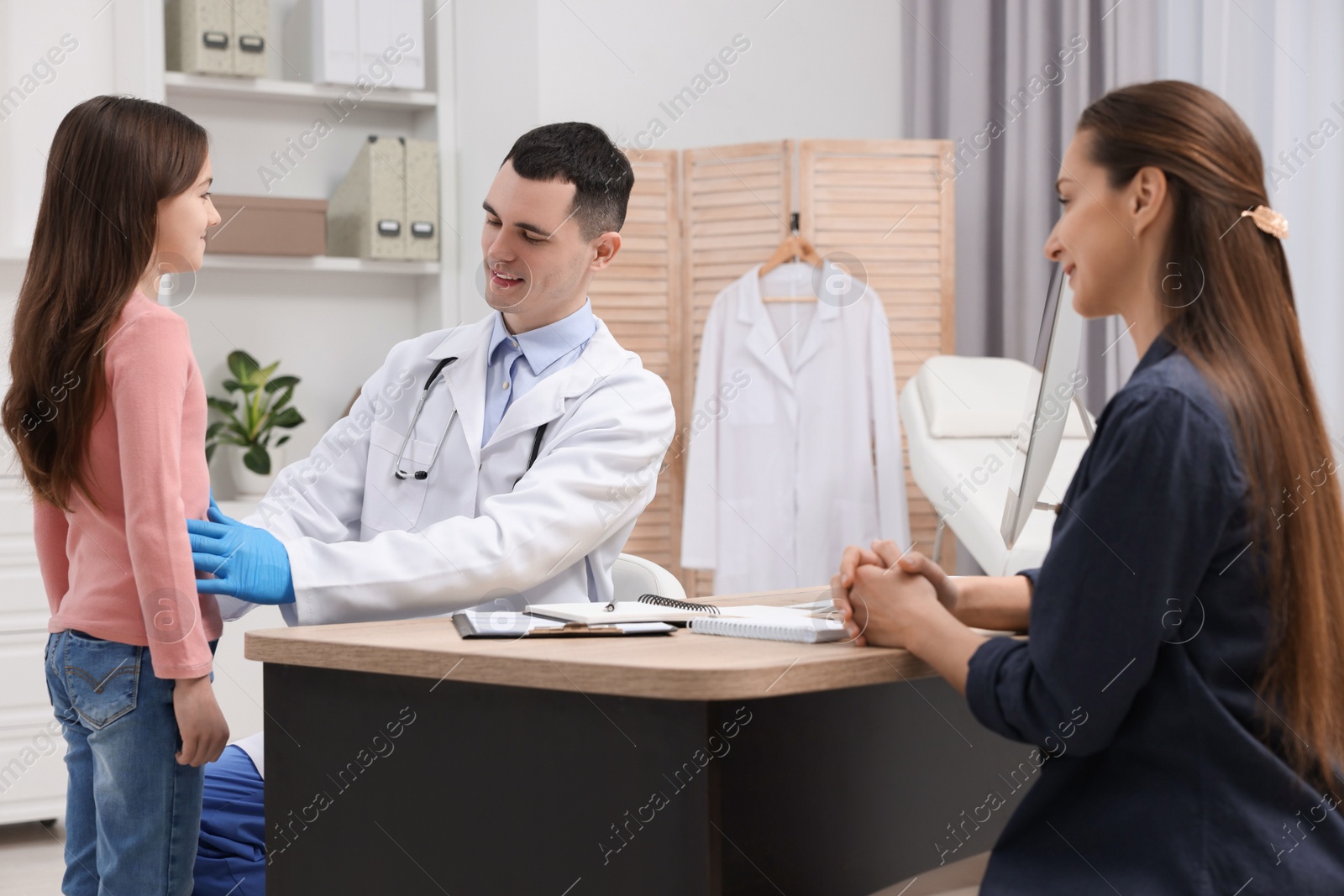 Photo of Gastroenterologist examining girl with stomach ache in clinic