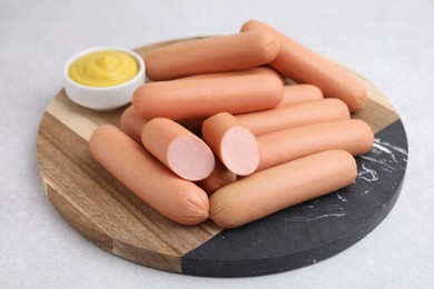 Photo of Delicious boiled sausages and sauce on light gray table, closeup