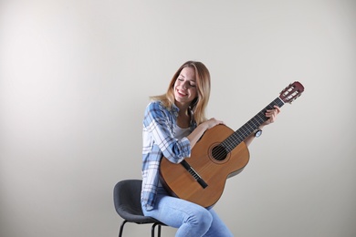 Young woman with acoustic guitar on grey background. Space for text