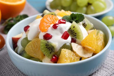 Photo of Delicious fruit salad with yogurt in bowl, closeup