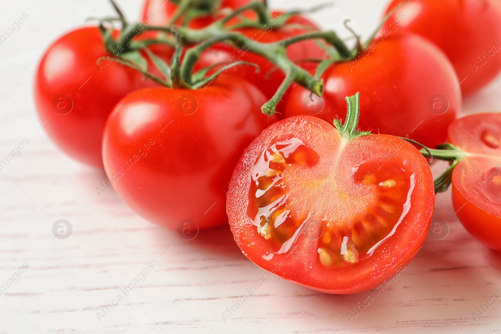 Photo of Fresh cherry tomatoes on white wooden background, closeup