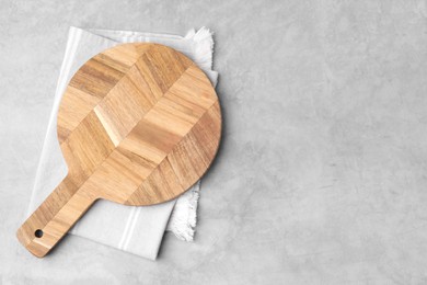 Photo of One wooden cutting board on light grey table, top view with space for text. Cooking utensil
