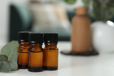 Photo of Aromatherapy. Bottles of essential oil and eucalyptus leaves on white table, space for text