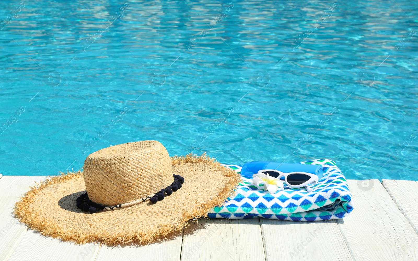 Photo of Beach accessories on wooden deck near swimming pool. Space for text