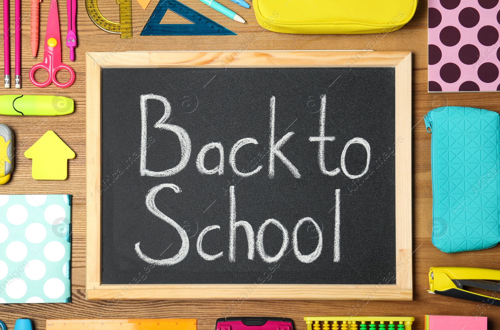 Photo of Flat lay composition with different school stationery and small chalkboard on wooden background