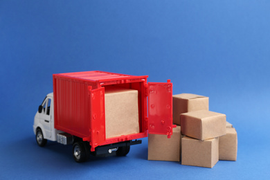 Photo of Truck model and carton boxes on blue background. Courier service