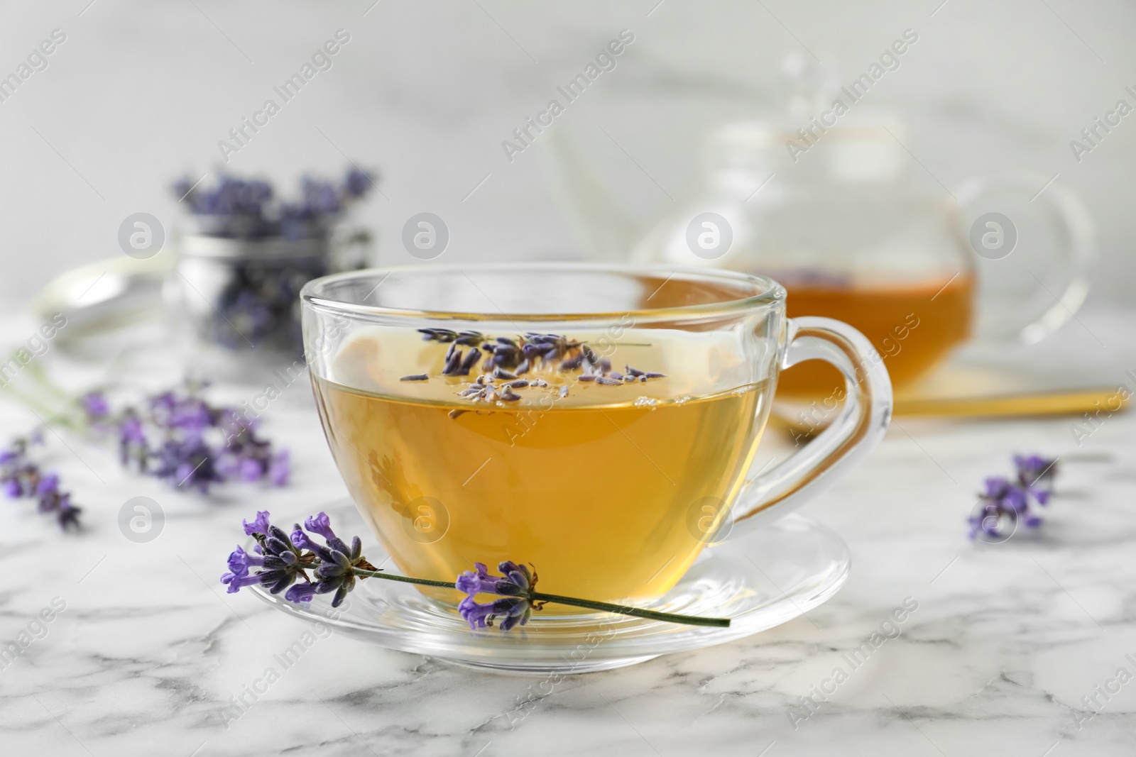 Photo of Fresh delicious tea with lavender and beautiful flowers on white marble table