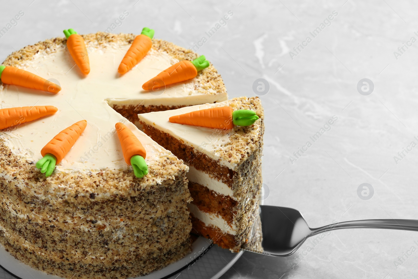 Photo of Sweet carrot cake with delicious cream and server on grey marble table, closeup