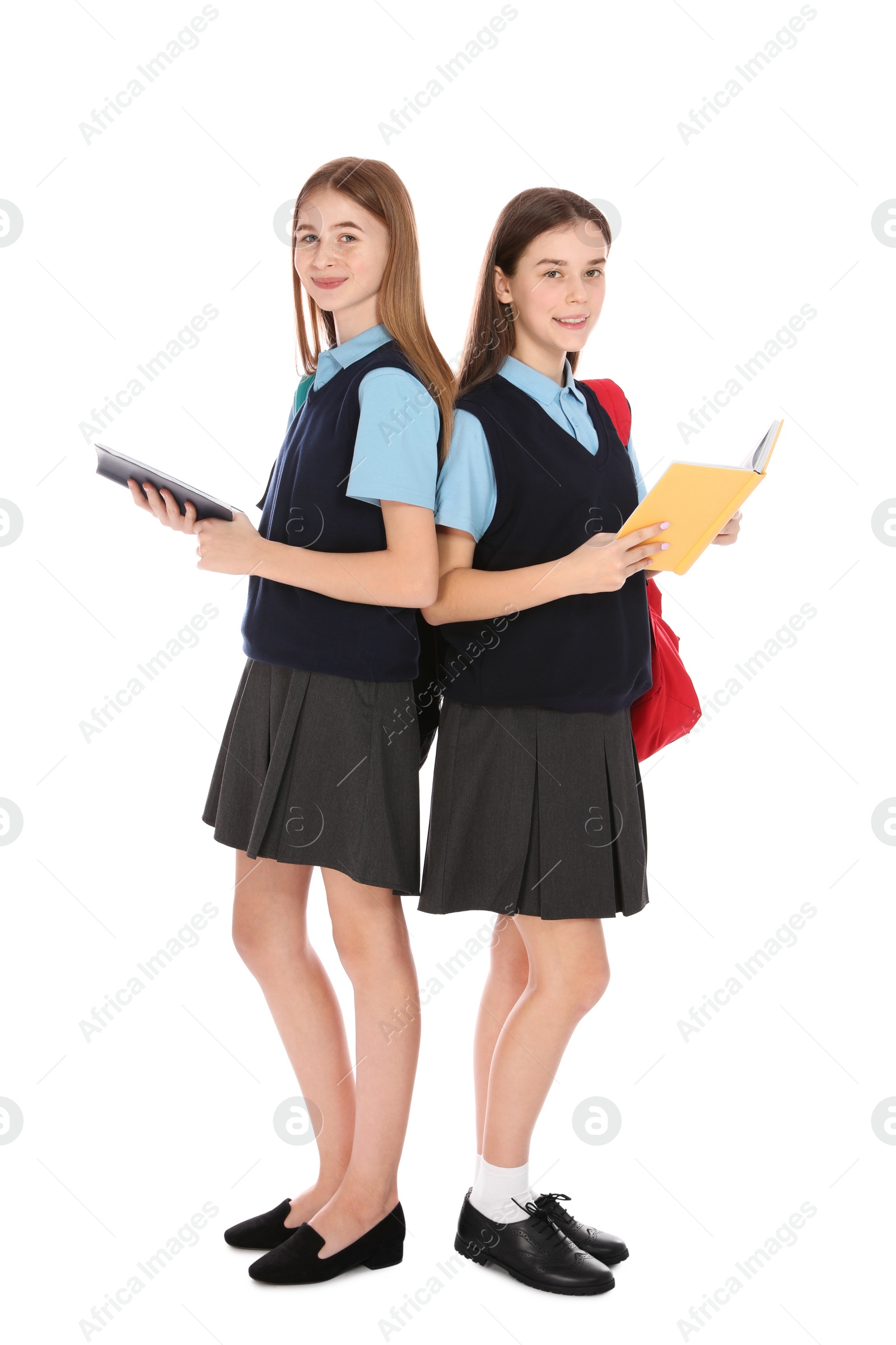 Photo of Full length portrait of teenage girls in school uniform with books on white background