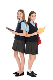 Full length portrait of teenage girls in school uniform with books on white background