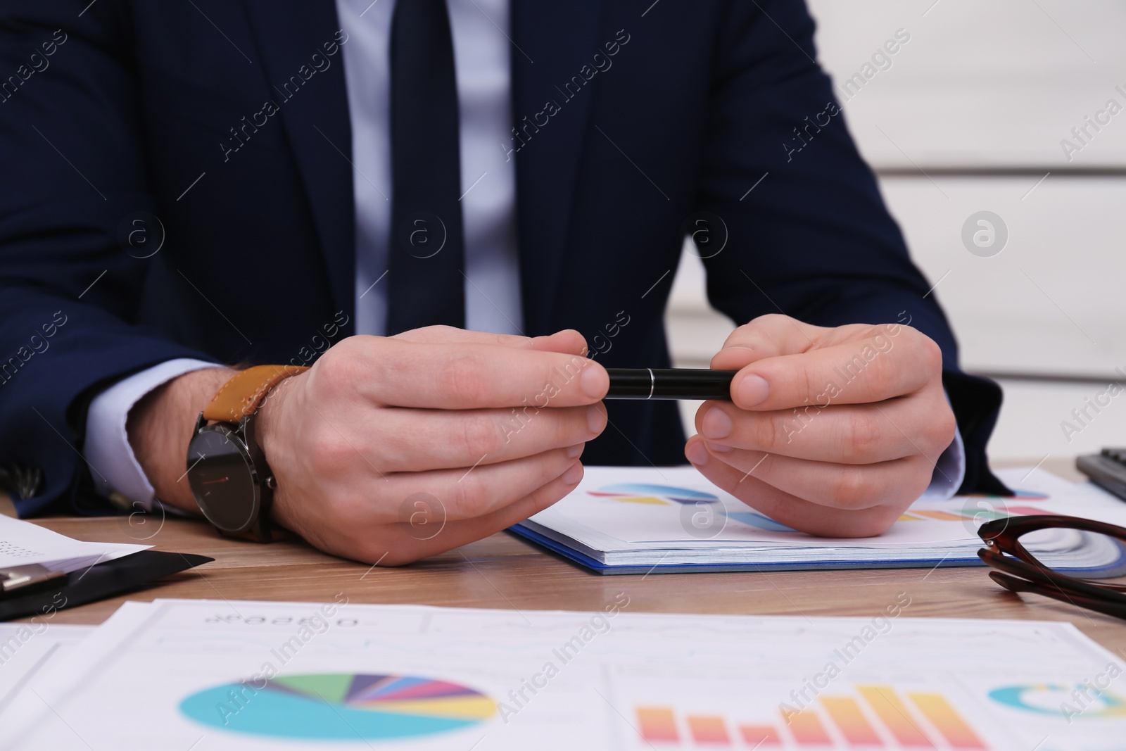 Photo of Businessman working with documents at table in office, closeup. Investment analysis