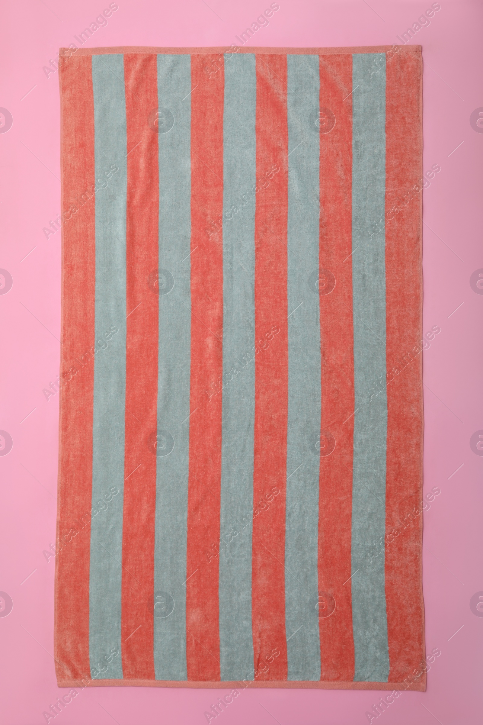Photo of Striped beach towel on pink background, top view