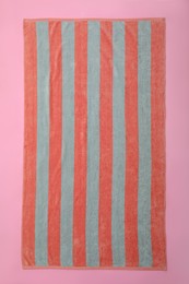 Striped beach towel on pink background, top view