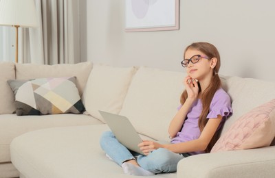 Photo of Thoughtful girl with laptop on sofa at home