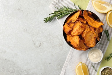 Flat lay composition with bowl of sweet potato chips and lemon on light table. Space for text