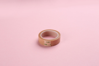 Photo of Medical sticking plaster roll on pink background