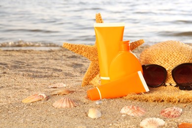 Sun protection products and beach accessories on sand near sea