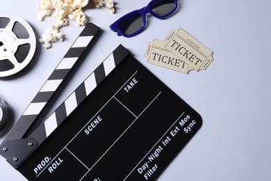Photo of Flat lay composition with clapperboard, film reel and 3D glasses on grey background, space for text