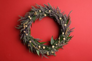 Photo of Beautiful heather wreath on red background, top view. Autumnal flowers