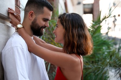 Happy young couple hugging near wall on city street