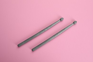 Two grey drumsticks on pink background, top view