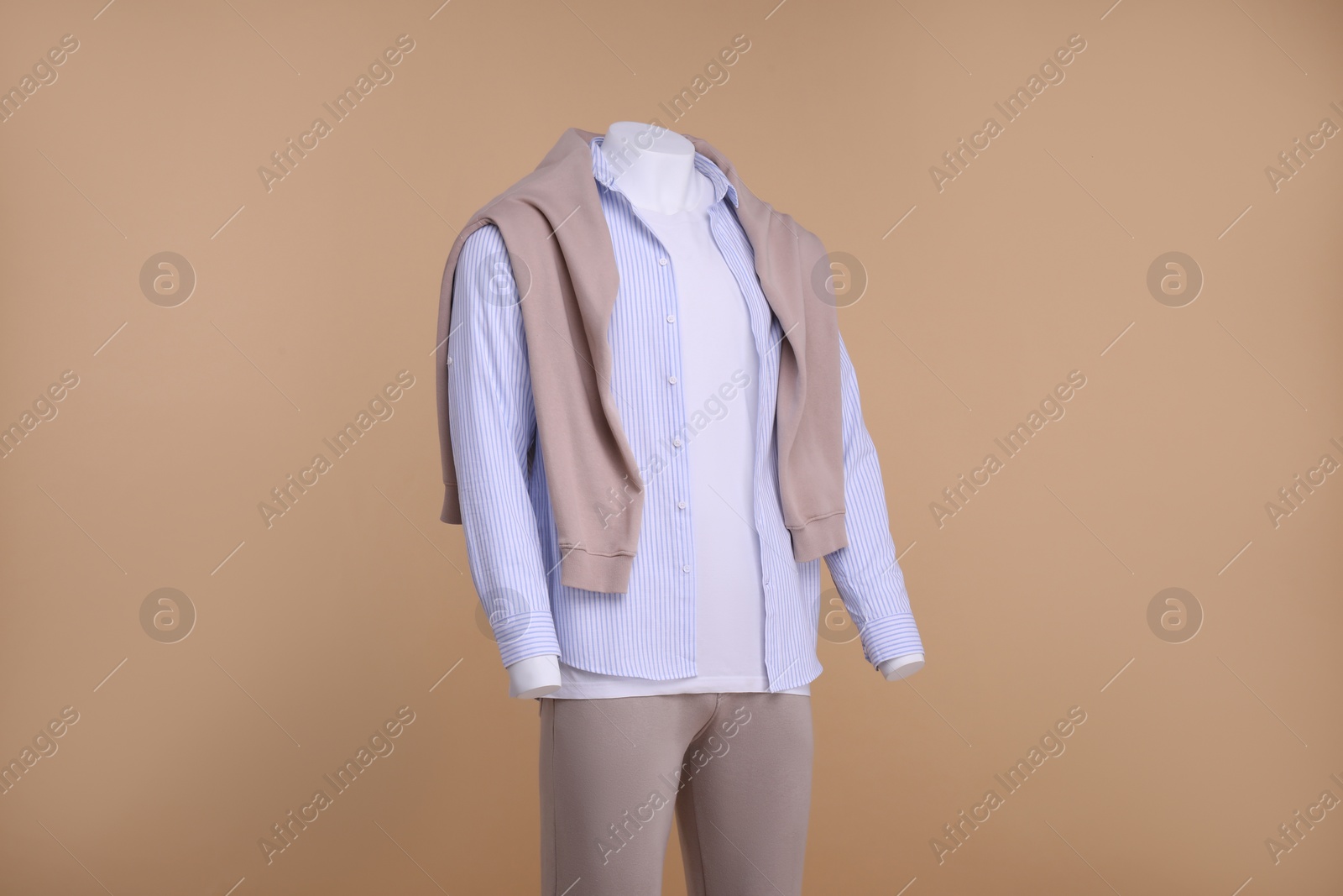 Photo of Male mannequin dressed in white t-shirt, sweater, striped shirt and pants on beige background