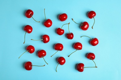 Photo of Many ripe sweet cherries on light blue background, flat lay