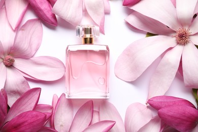 Photo of Beautiful pink magnolia flowers and bottle of perfume on white background, flat lay