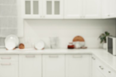 Photo of White stylish kitchen with furniture, blurred view. Interior design