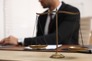 Lawyer working at table in office, focus on scales of justice