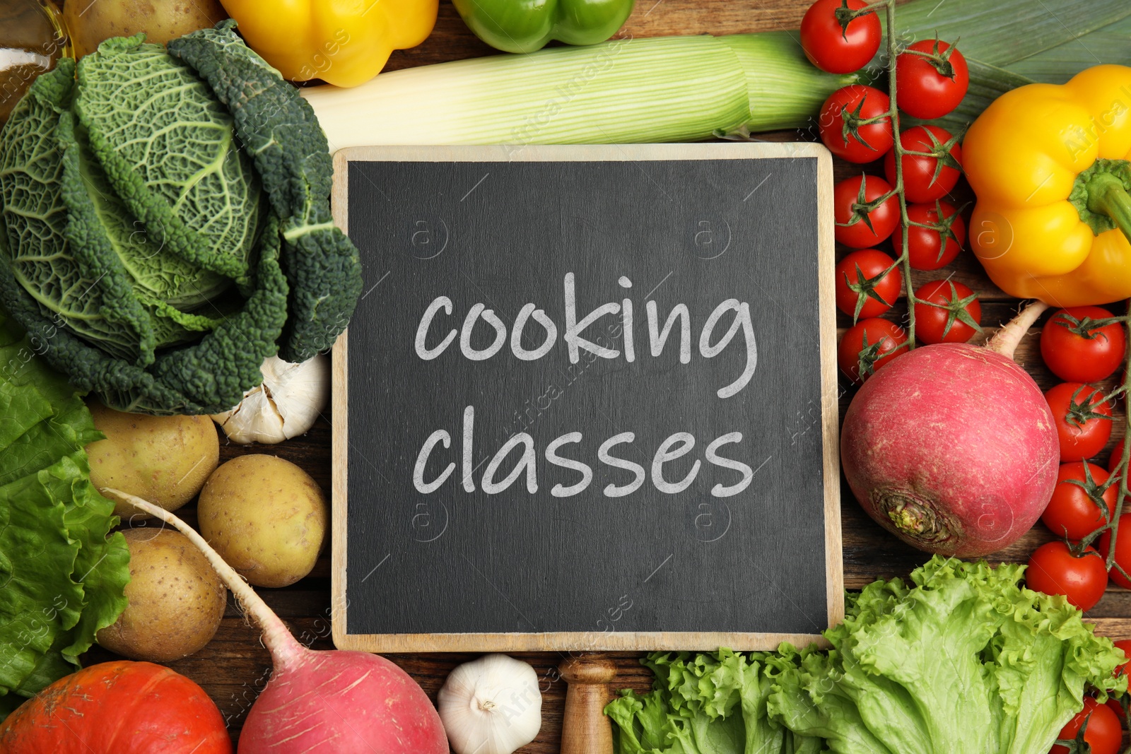 Image of Small chalkboard with inscription Cooking Classes and different fresh vegetables on wooden table, flat lay