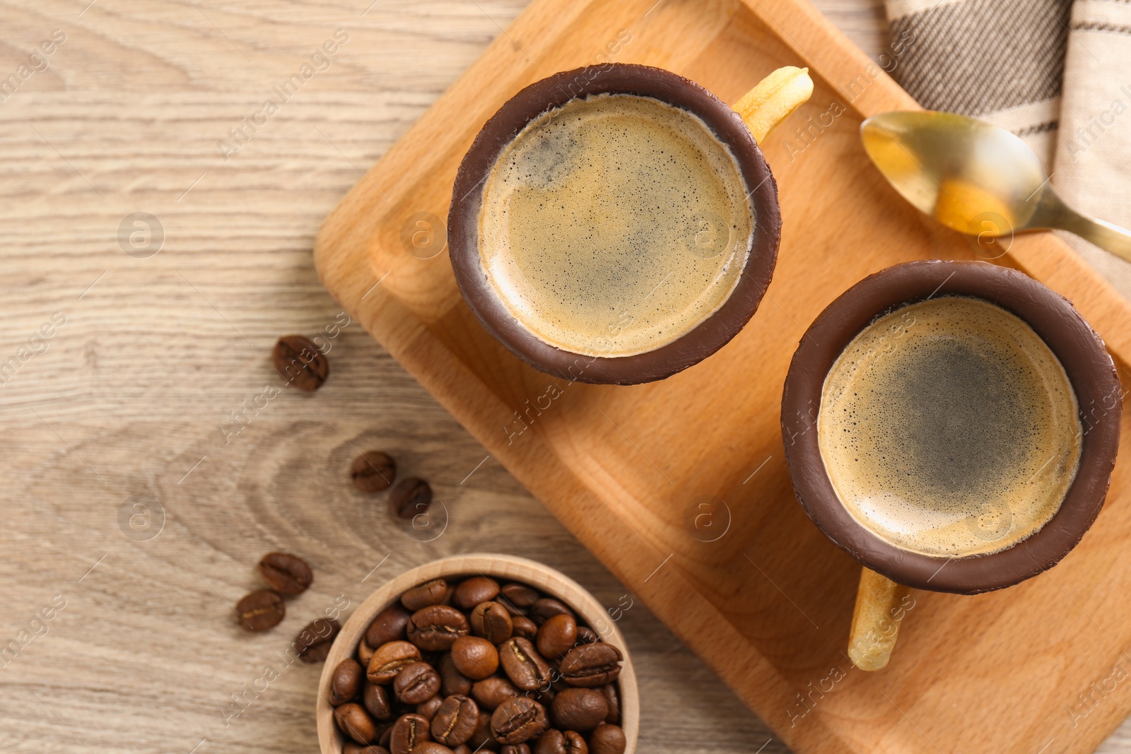 Photo of Delicious biscuit cups with espresso, spoon and coffee beans on wooden table, flat lay. Space for text