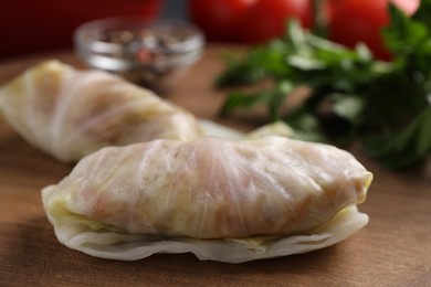 Uncooked stuffed cabbage rolls on wooden board, closeup