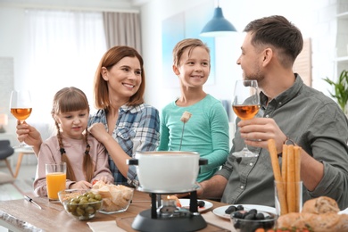 Photo of Happy family enjoying fondue dinner at home