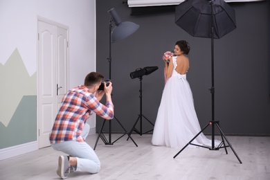 Photo of Professional photographer taking photo of beautiful bride in studio