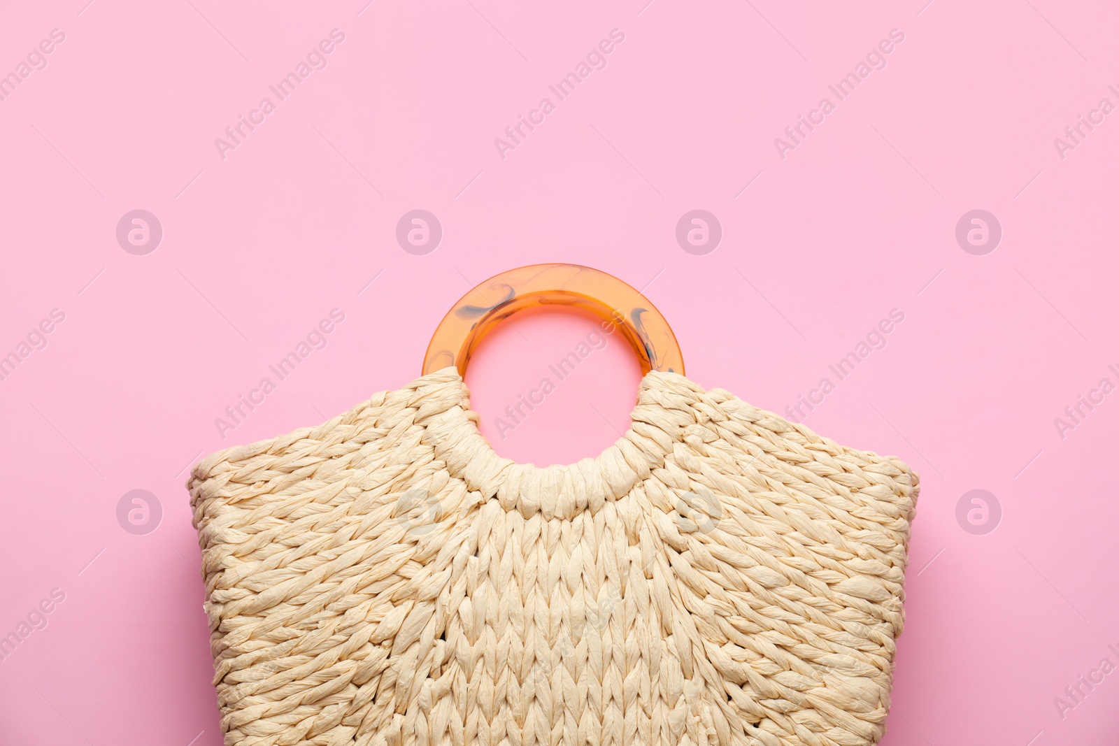 Photo of Elegant woman's straw bag on pink background, top view