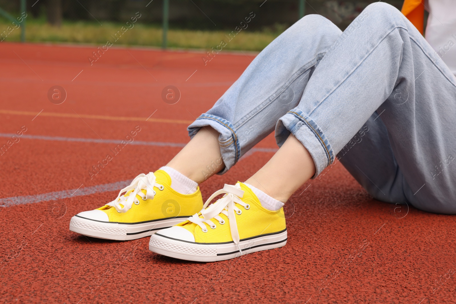 Photo of Woman wearing yellow classic old school sneakers on court outdoors, closeup