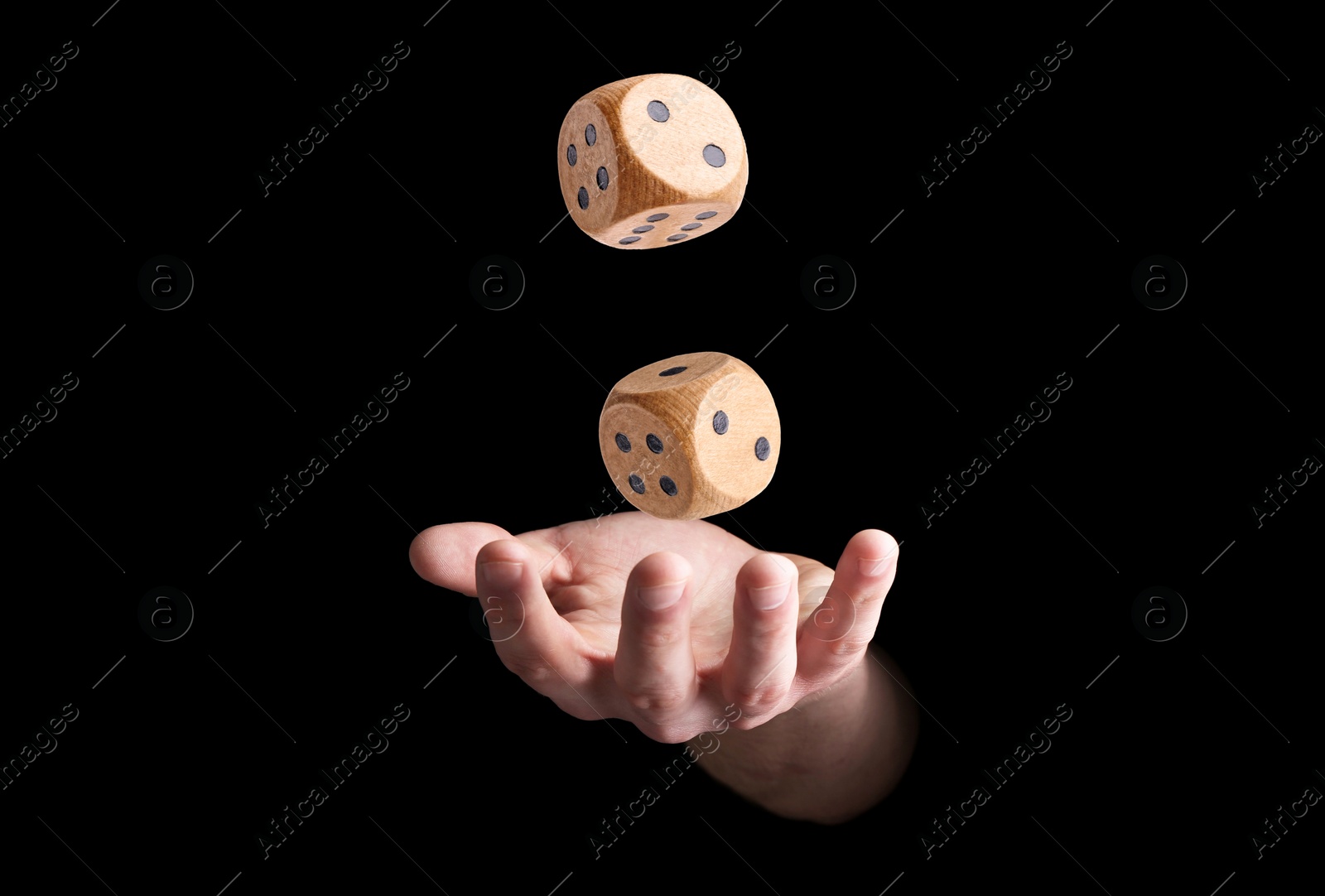 Image of Man throwing wooden dice on black background, closeup